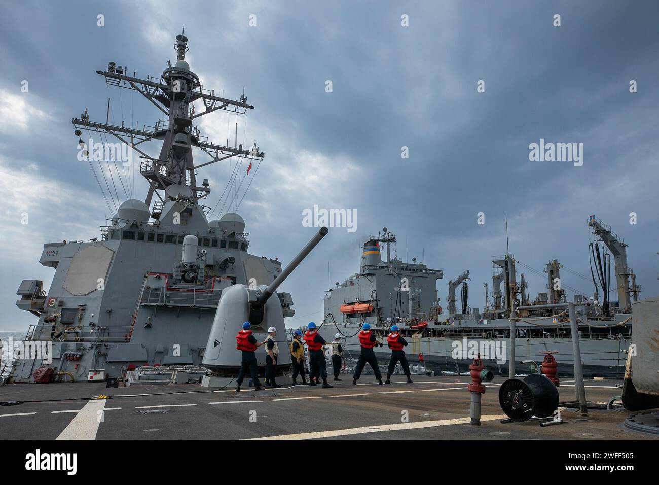 U.S. Navy Sailors assegnato alla linea di heave del cacciatorpediniere guidato USS Laboon (DDG 58) durante un rifornimento in mare con l'oliatore di rifornimento della flotta USNS Kanawha (T-AO 196) nel Mar Rosso, 17 gennaio 2024. Laboon è schierato nell'area operativa della 5th Fleet degli Stati Uniti per sostenere la sicurezza marittima e la stabilità in Medio Oriente. (Foto della Marina degli Stati Uniti di Mass Communication Specialist di terza classe Alice Husted) Foto Stock