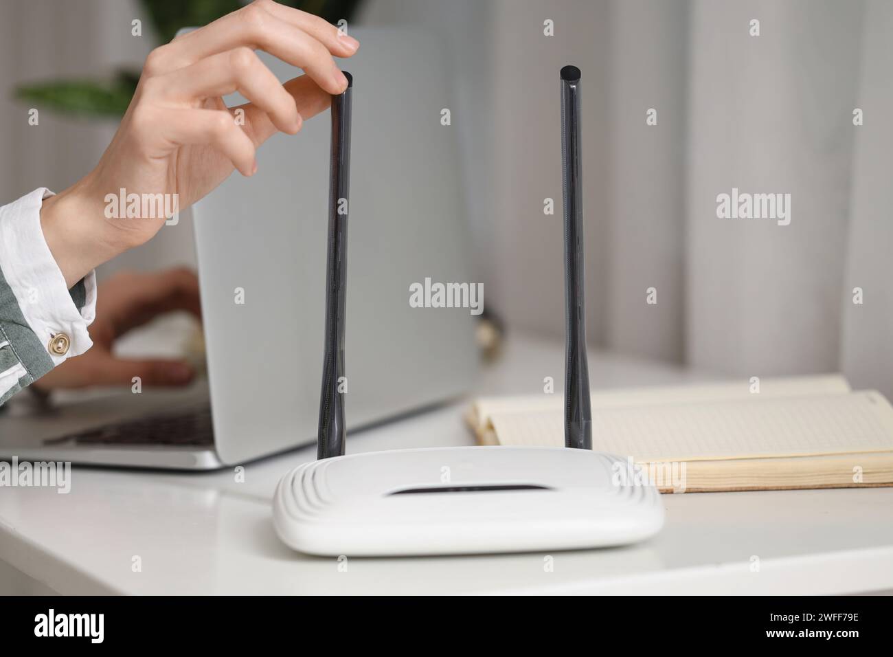 Moderno router wi-fi su un tavolo di donna che lavora con un laptop, primo piano Foto Stock