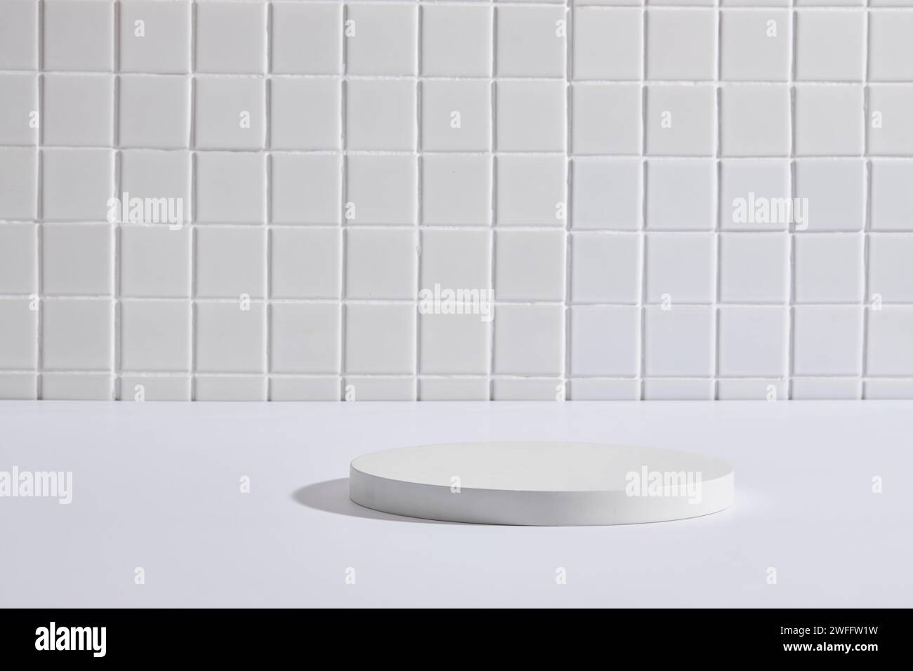 Scena minimalista di un podio bianco di forma rotonda con spazio vuoto su uno sfondo di tessere a mosaico bianco. Spazio libero per visualizzare il prodotto Foto Stock