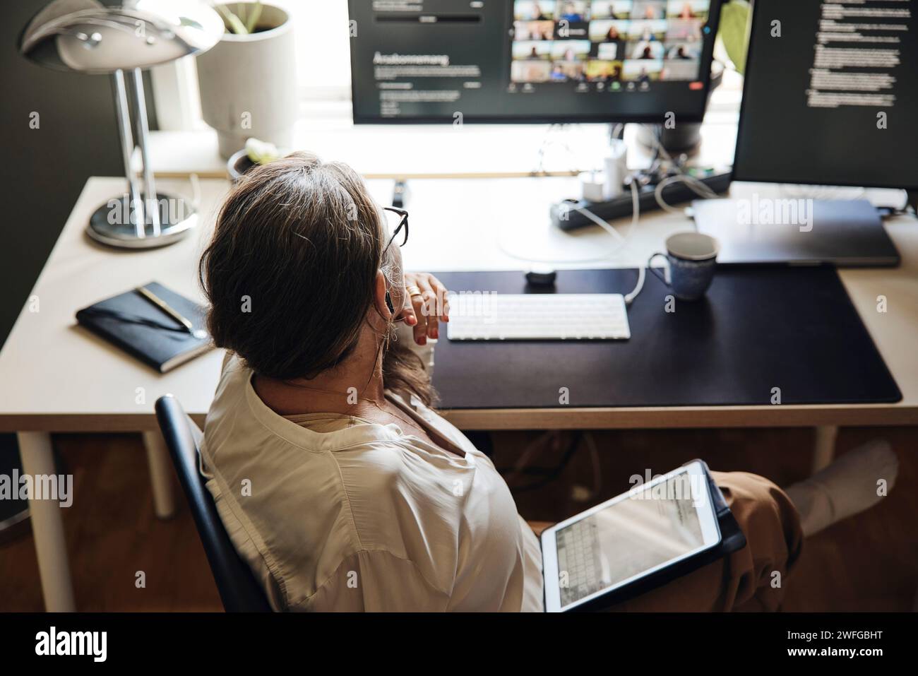Vista ad alto angolo del freelance seduto con un tablet PC alla scrivania in ufficio Foto Stock