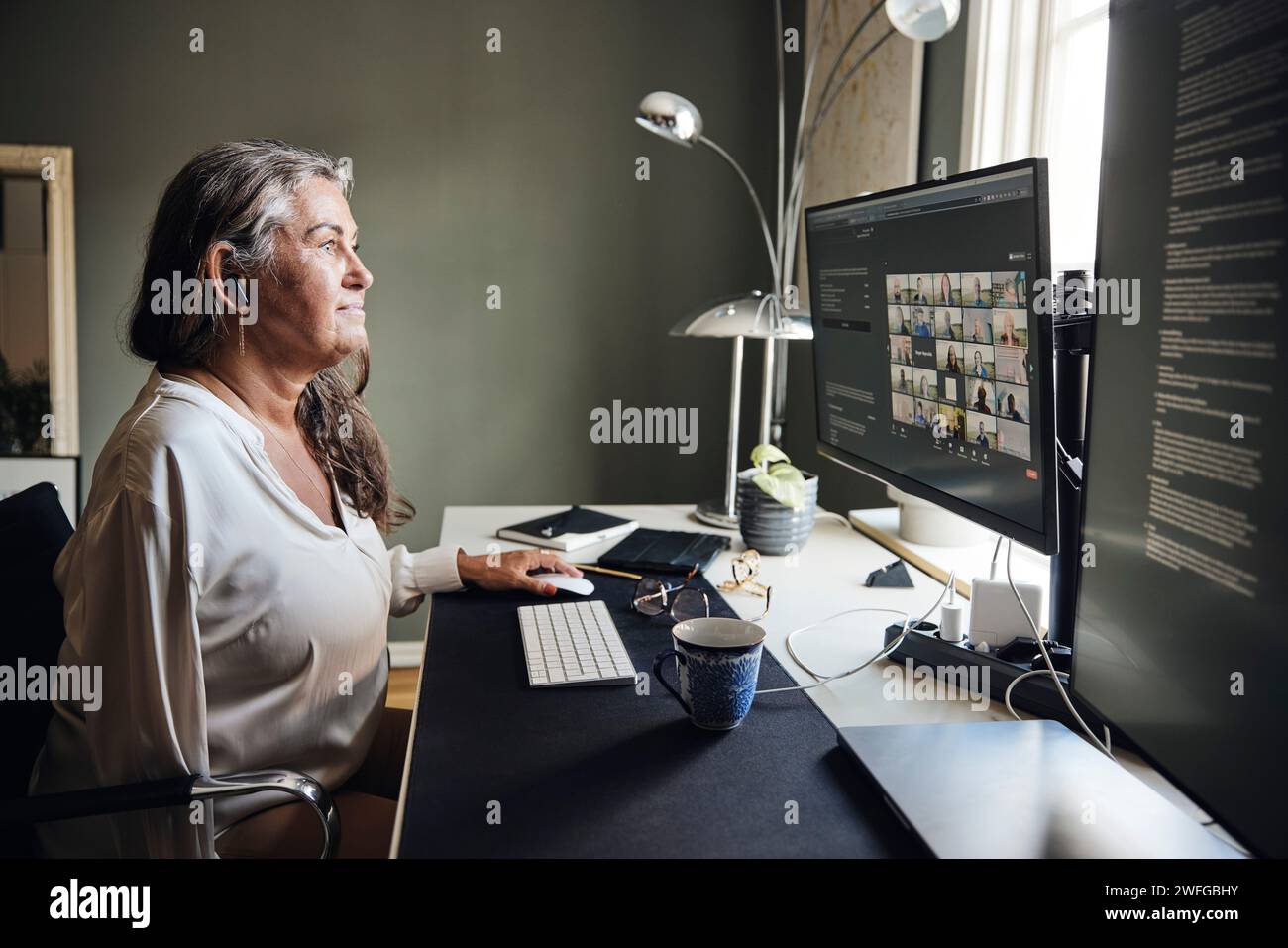 Donna d'affari che fa videoconferenze tramite computer mentre è seduta alla scrivania in ufficio Foto Stock