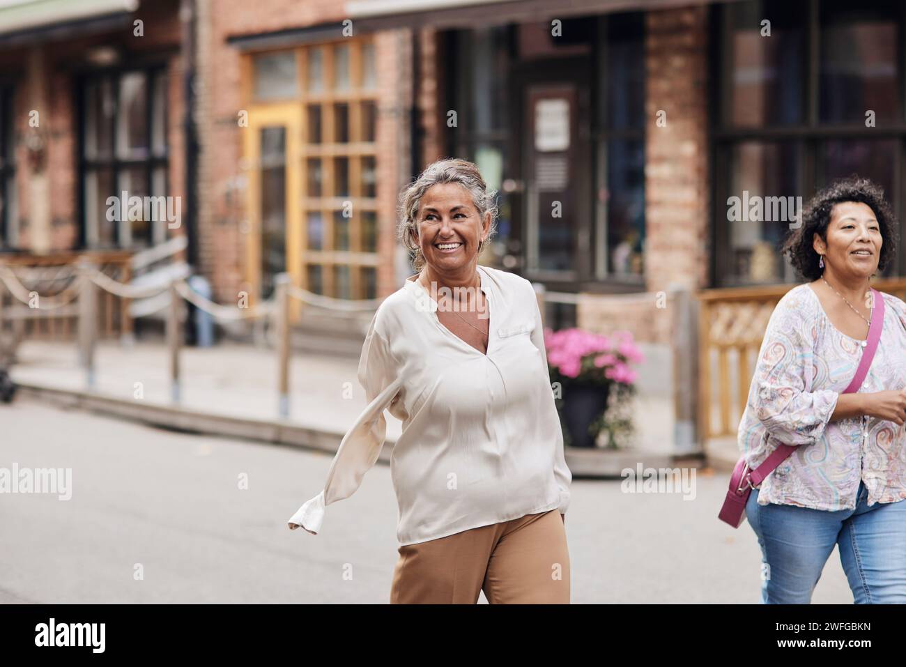 Donna disabile sorridente che passeggia con un'amica mentre cammina per strada Foto Stock