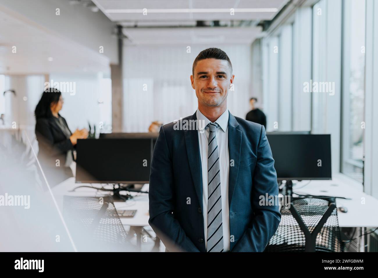 Ritratto di un giovane uomo d'affari sorridente in piedi all'ufficio aziendale Foto Stock