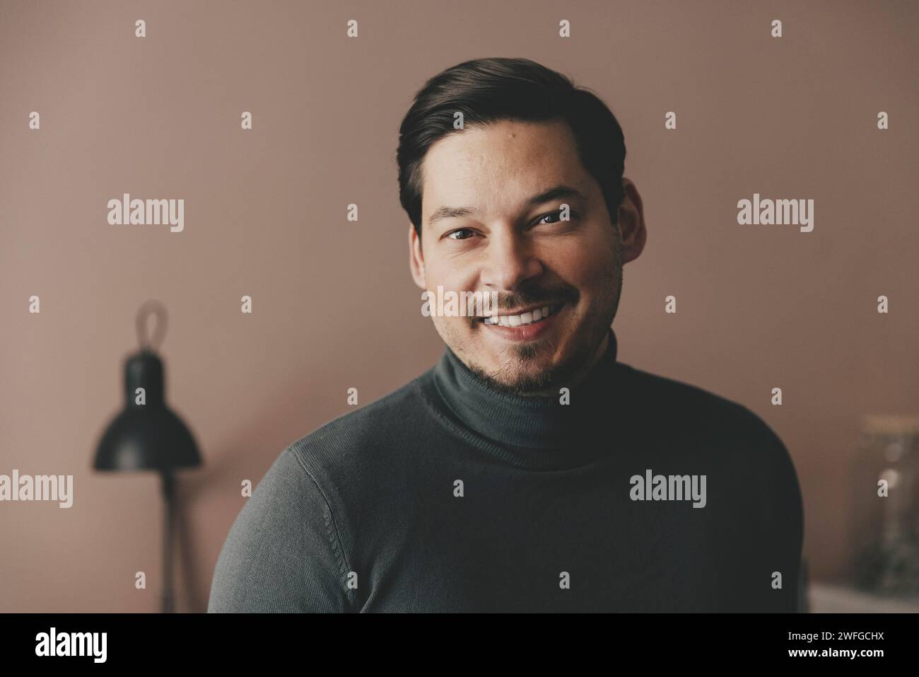 Ritratto di un uomo d'affari sorridente che indossa dolcevita in ufficio Foto Stock