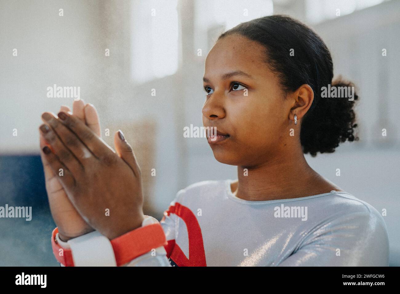 Ginnasta femminile contemplativa che applica polvere di gesso in palestra Foto Stock
