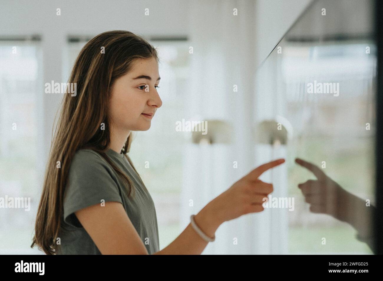 Vista laterale della ragazza che utilizza lo Smart TV mentre si è a casa Foto Stock