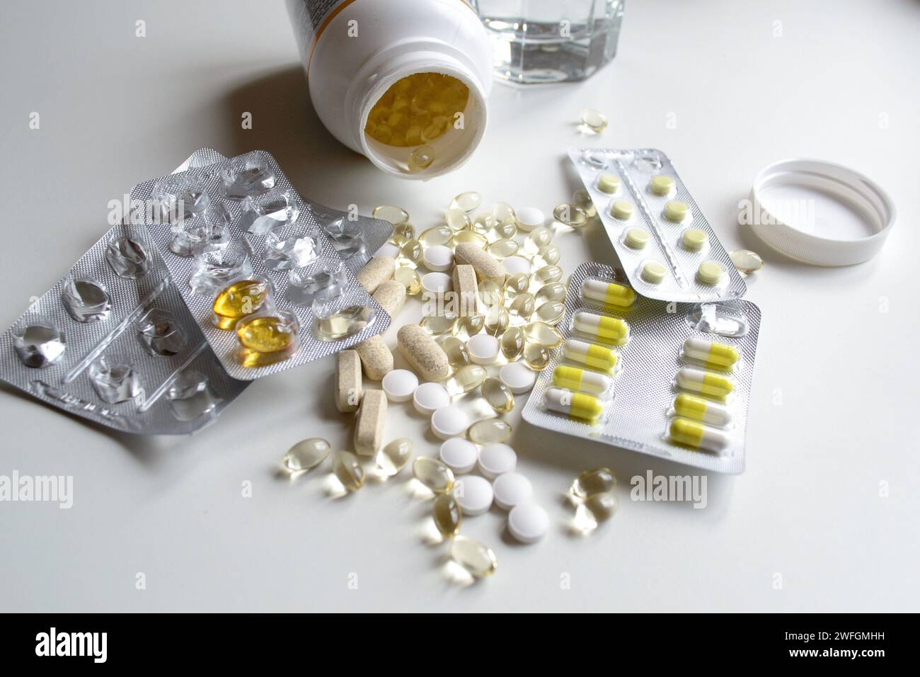 Molte diverse vitamine e compresse in confezioni e senza su un tavolo bianco Foto Stock