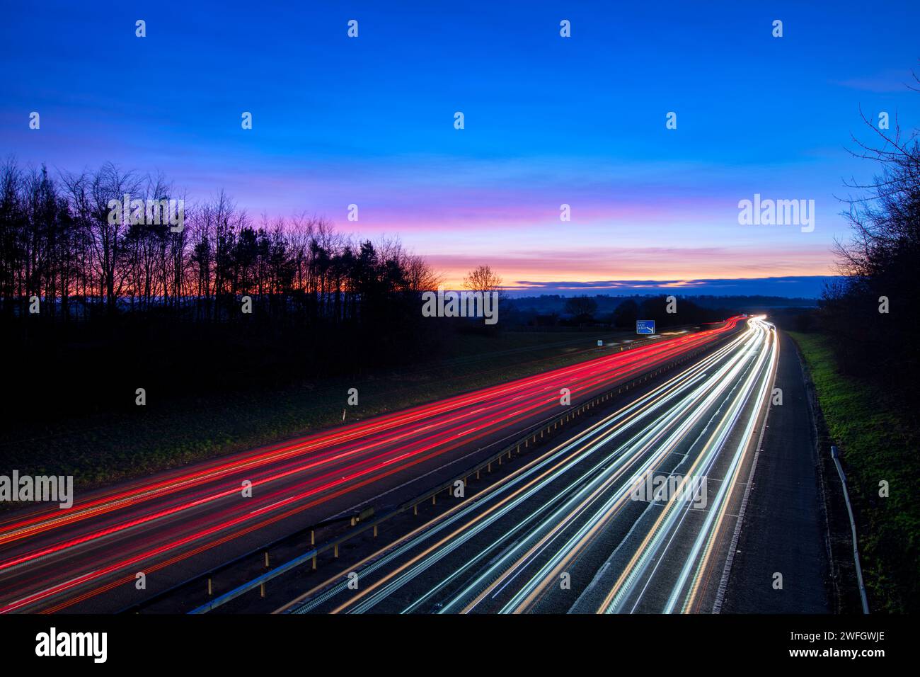 Colore dell'alba sull'autostrada M40 con sentieri leggeri per auto. Banbury, Oxfordshire, Inghilterra Foto Stock
