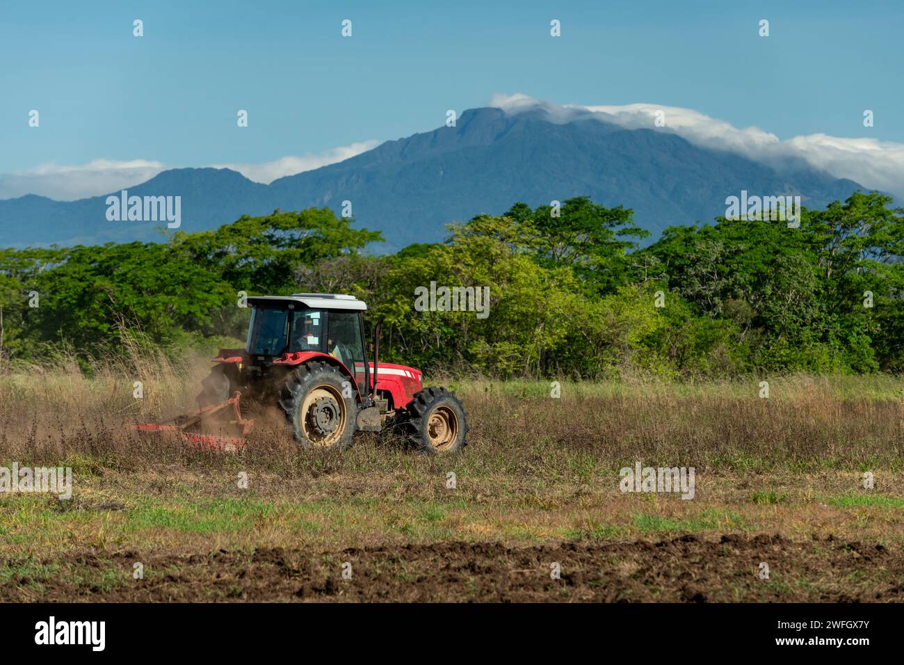 Cielo blu sopra il trattore arando un campo con il vulcano Baru sullo sfondo, Chiriqui, Panama, America centrale - foto stock Foto Stock