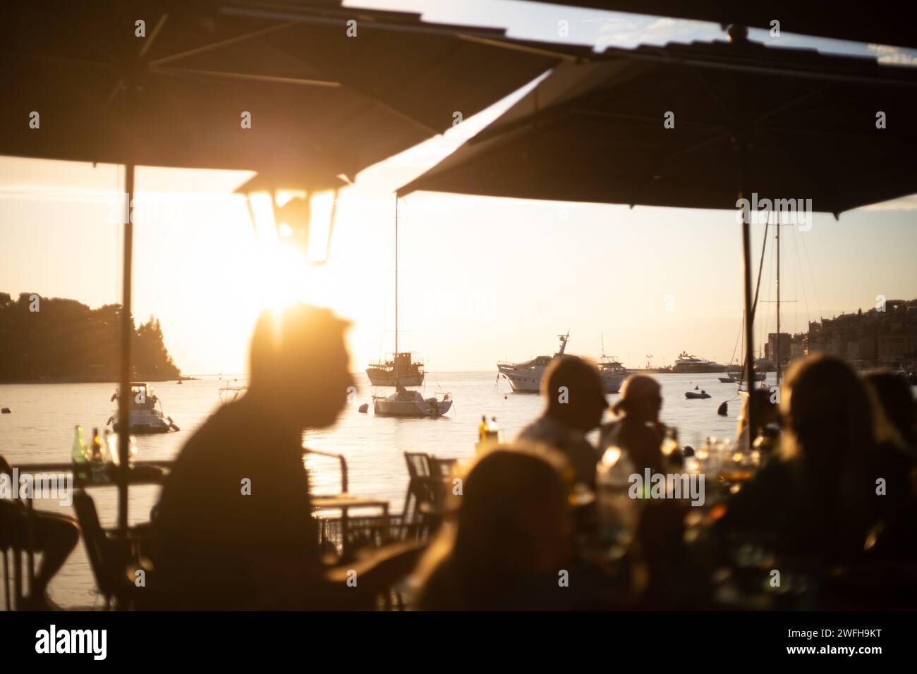persone che cenano al ristorante sul mare con un tramonto romantico Foto Stock