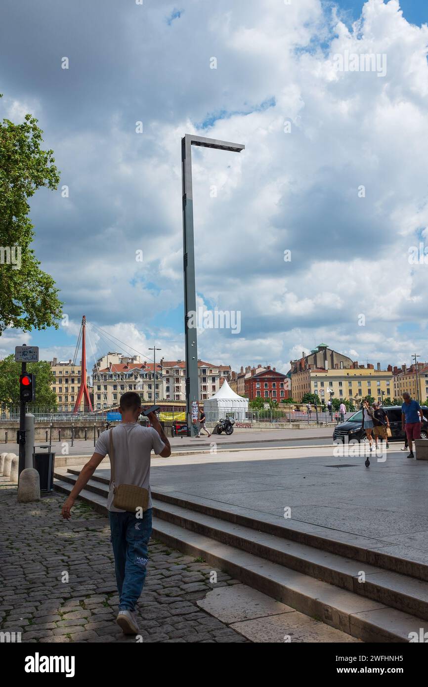 Lione, Francia, 2023. Un giovane sta camminando verso il Quai Romain Rolland e la passerella pedonale del Palais de Justice (verticale) Foto Stock