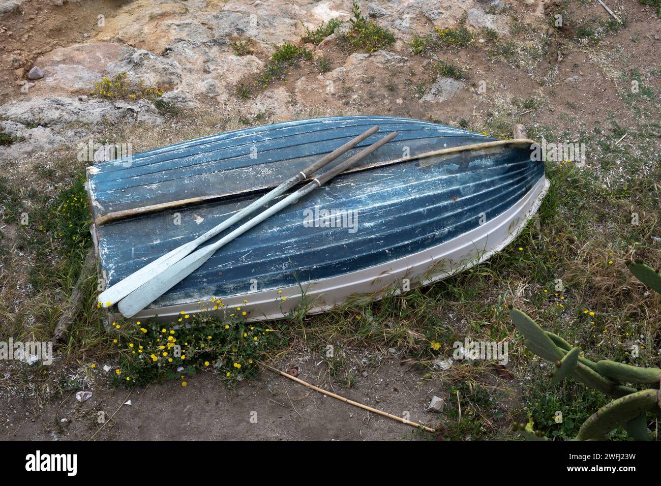 Remi in cima a una barca a remi rovesciata sulla costa nord-occidentale della Sardegna, Italia. Foto Stock