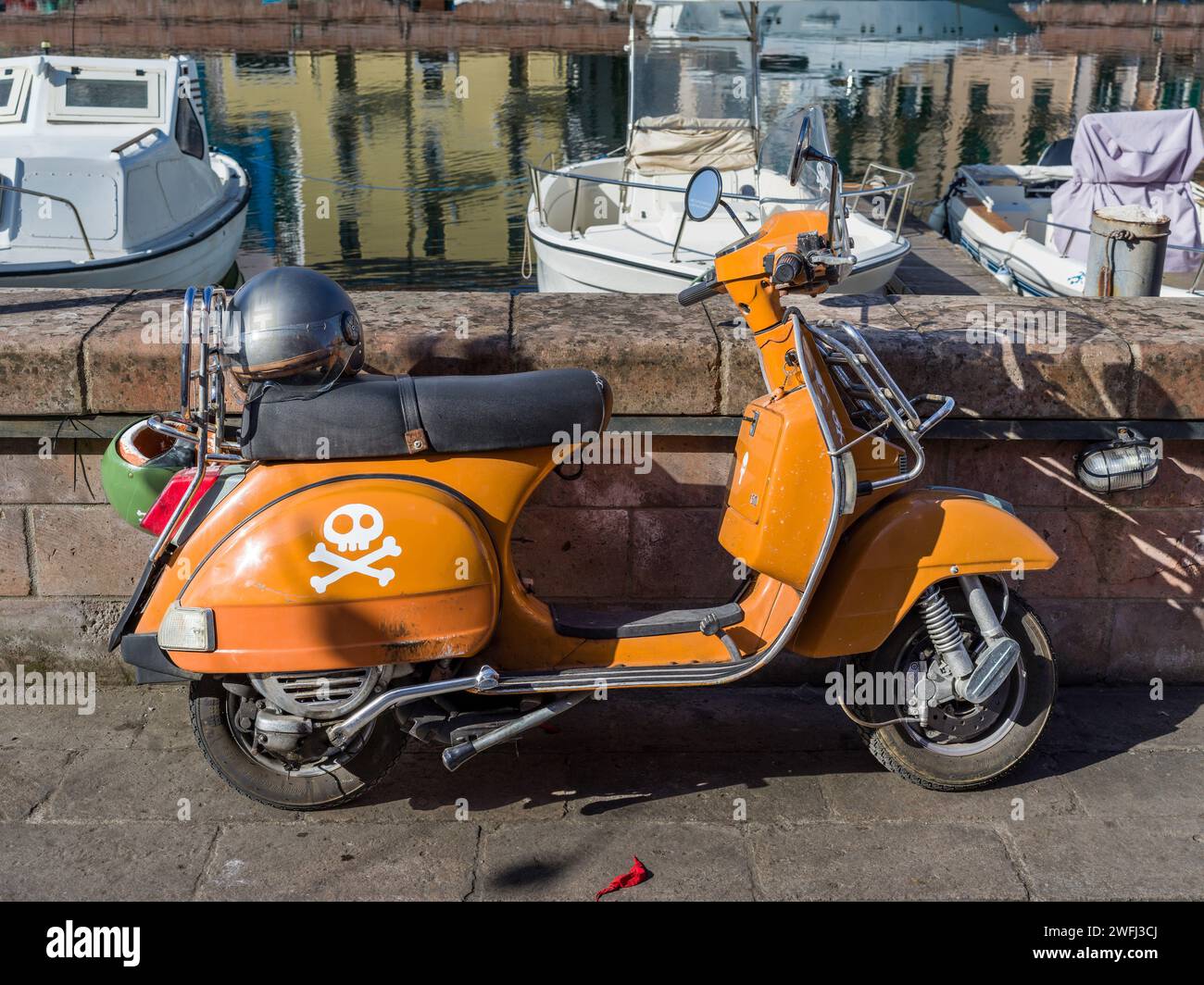 Scooter giallo parcheggiato lungo un molo nella città di Bosa, Sardegna, Italia Foto Stock
