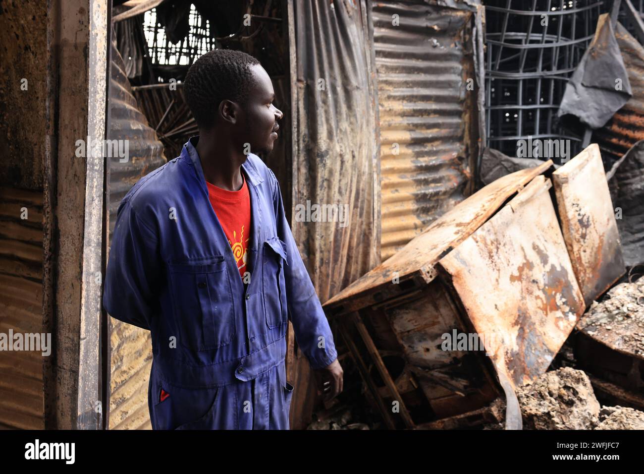 Un uomo è visto sulla scena in cui un mercato di commercianti su piccola scala è stato raso al suolo a Nairobi. I commercianti sono rimasti contando enormi perdite dovute all'incendio che ha bruciato i locali commerciali. Foto Stock