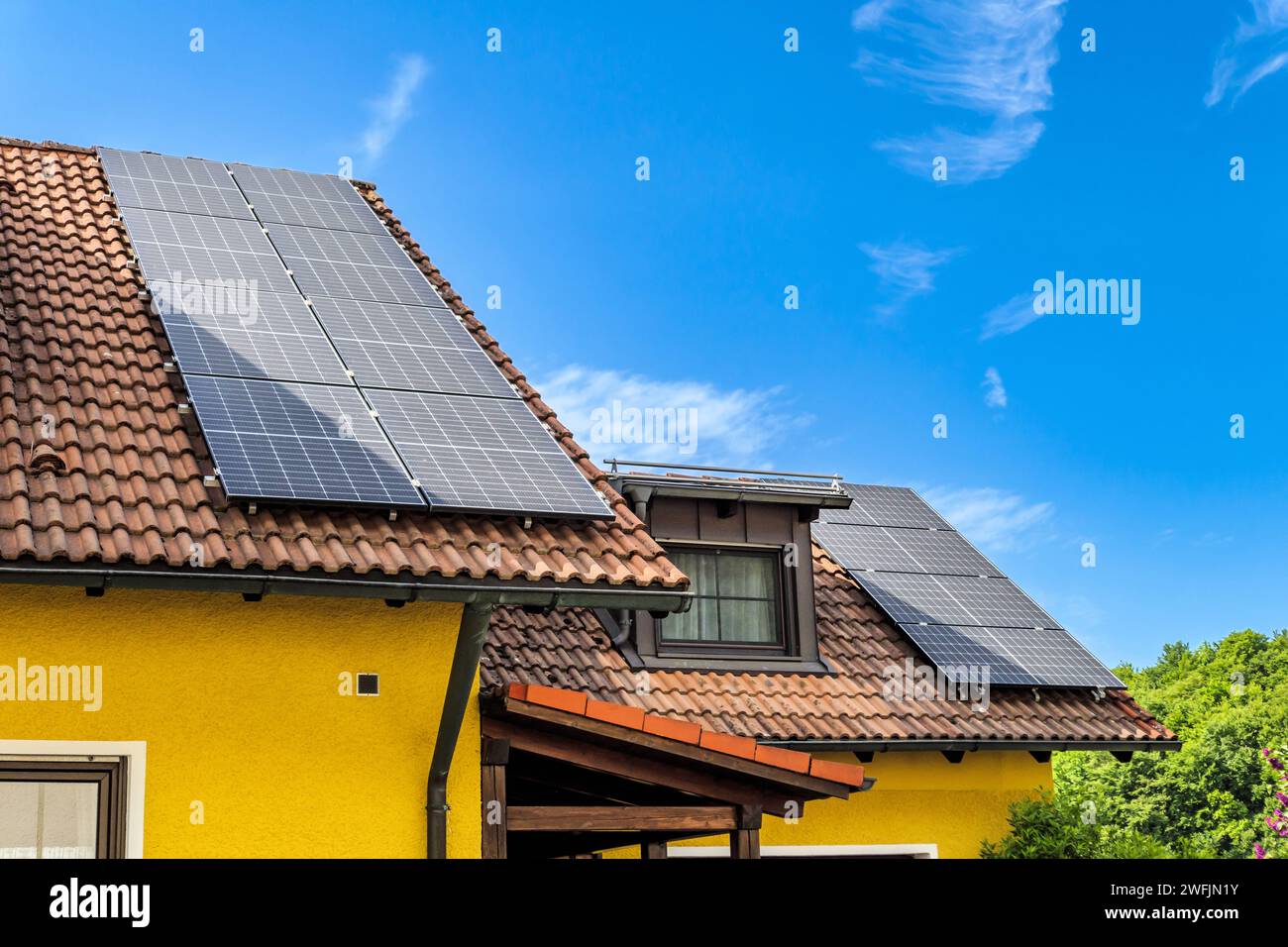 Tetti delle case con pannelli solari contro un cielo blu Foto Stock