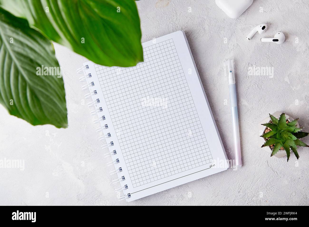 Eleganza minimalista dell'area di lavoro - aprite notebook, penna e auricolari con posizionamento piatto. Foto Stock