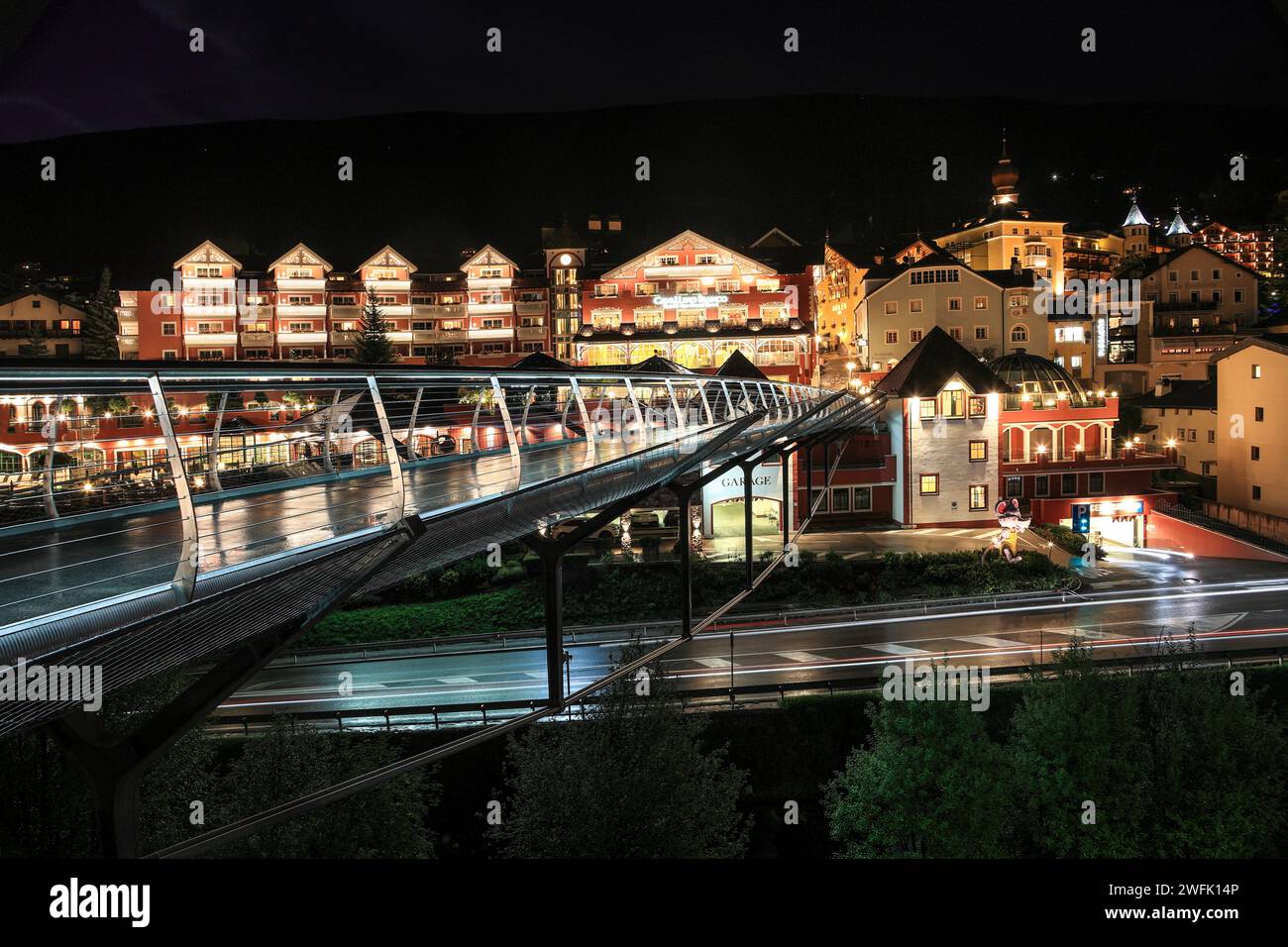 Oritsei, St. Ulrich, Italia - agosto 25. 2022: Vista notturna del centro di Ortisei con moderno ponte di vetro. E' una popolare attivita' turistica e all'aperto Foto Stock