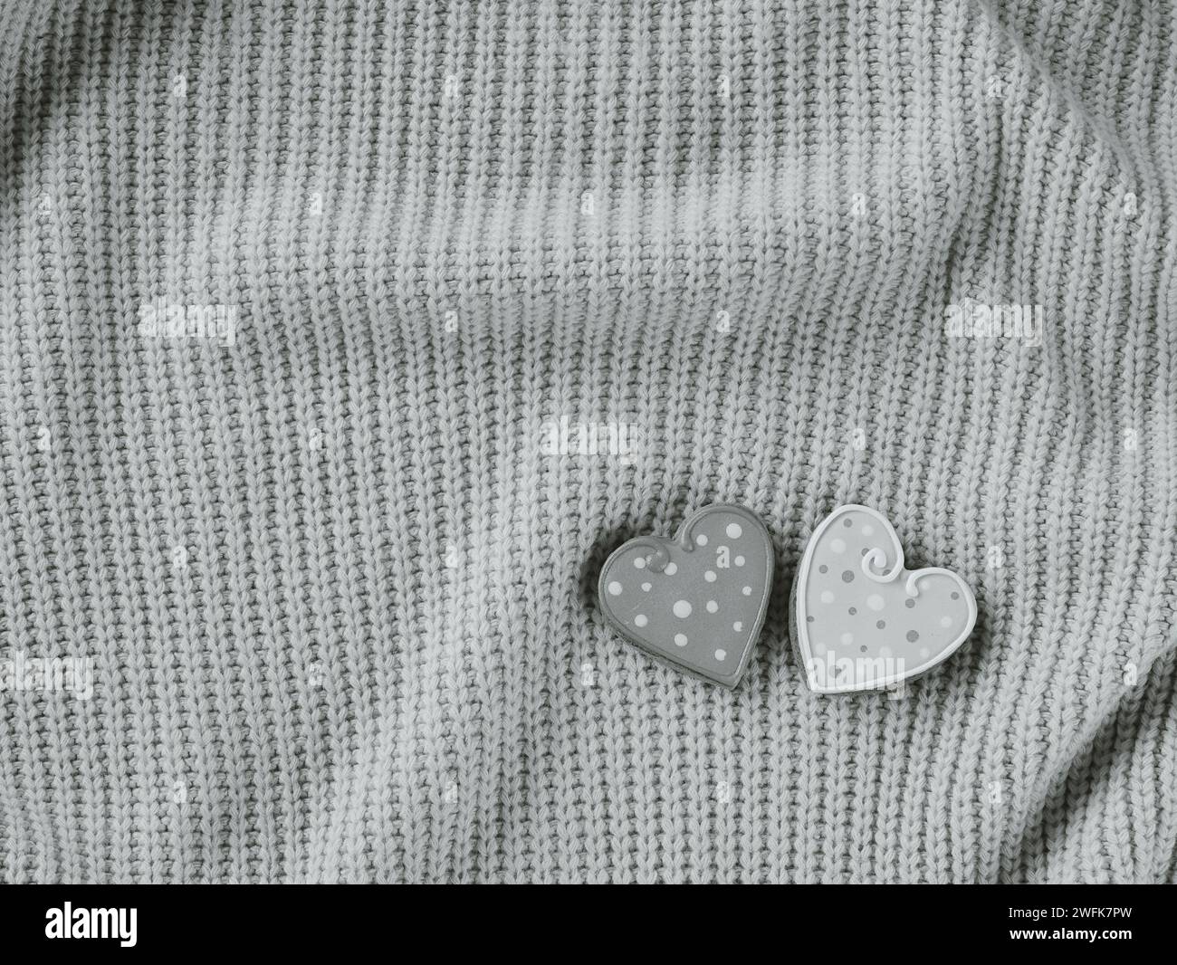 Due spille a forma di cuore con motivi a pois su tessuto lavorato a maglia. Bianco e nero Foto Stock