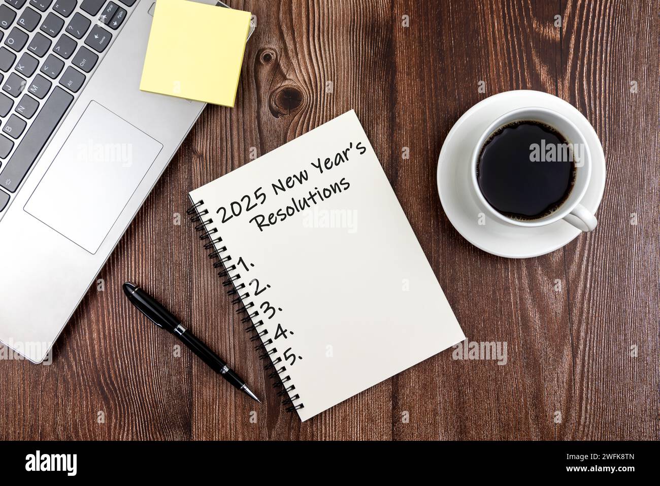 Risoluzioni di Capodanno 2025 testo su blocco note foto su scrivania in legno Foto Stock