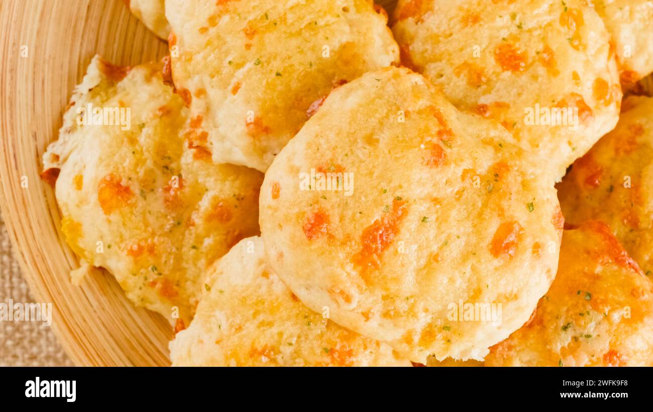 Biscotti al formaggio con burro e aglio condimento primo piano su un piatto di legno, vista dall'alto, mani di donna Foto Stock