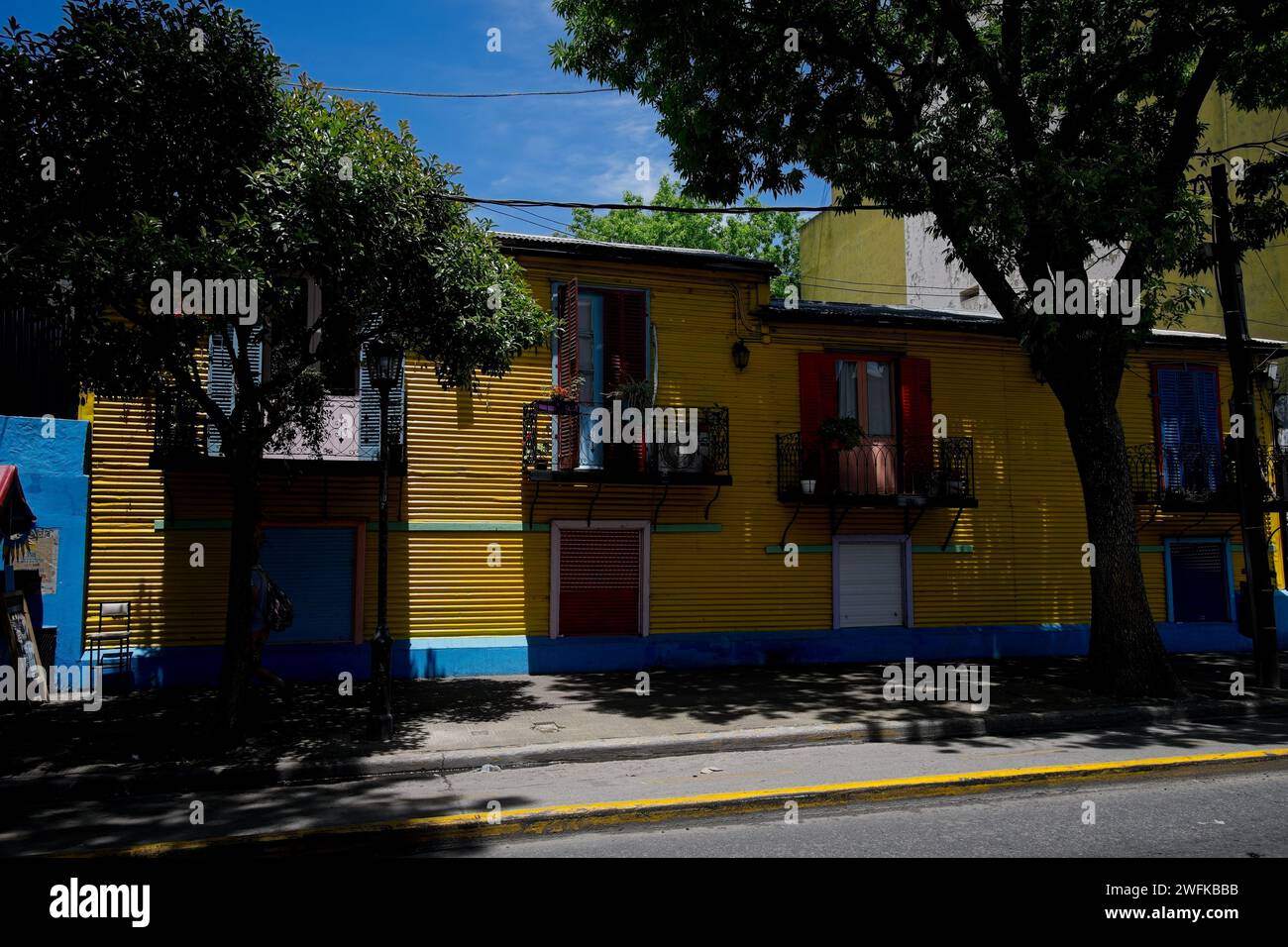 La Boca è un'area operaia con attrazioni colorate vicino al fiume Riachuelo. Ristoranti grill e artisti di strada circondano gli alberi Caminito.Shady Foto Stock