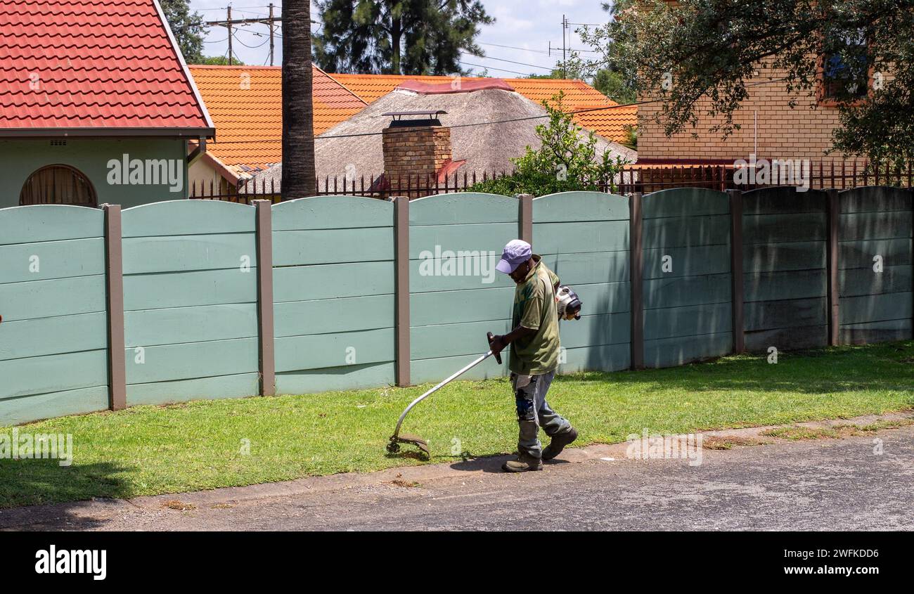 Johannesburg, Sudafrica - un lavoratore migrante non identificato fa lavori manuali di giardinaggio per guadagnarsi da vivere Foto Stock
