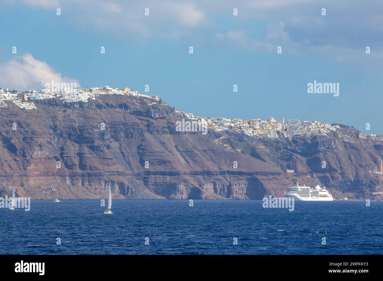 Santorini - le scogliere di calera con le crociere che percorrono il Thera e il Firostefani sullo sfondo. Foto Stock