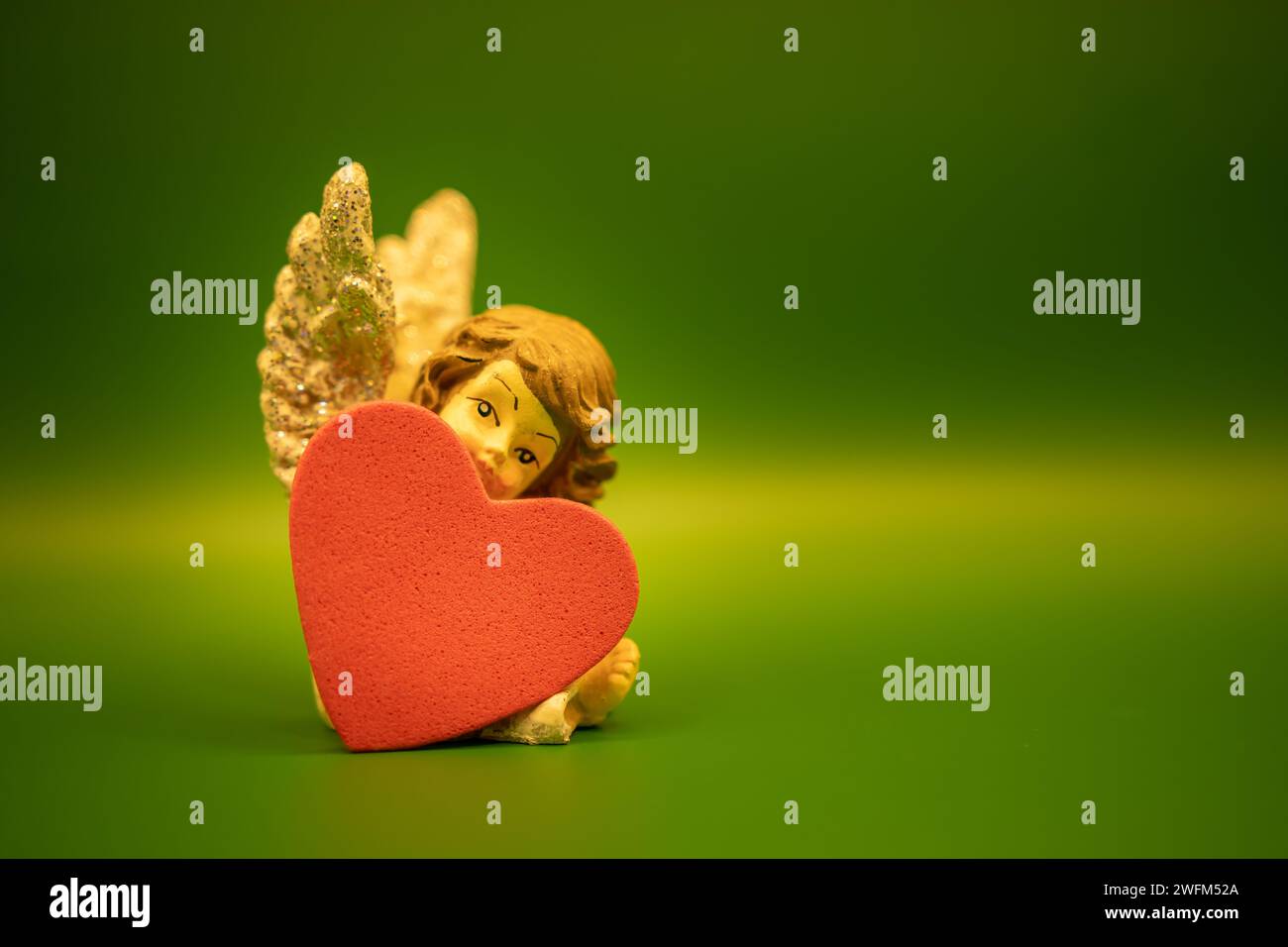 Un piccolo angelo e un focolare su sfondo verde. San Valentino, 14° concetto di febbraio. Ornamenti d'angelo di Natale. Concetto di Angelo e amore. Foto Stock