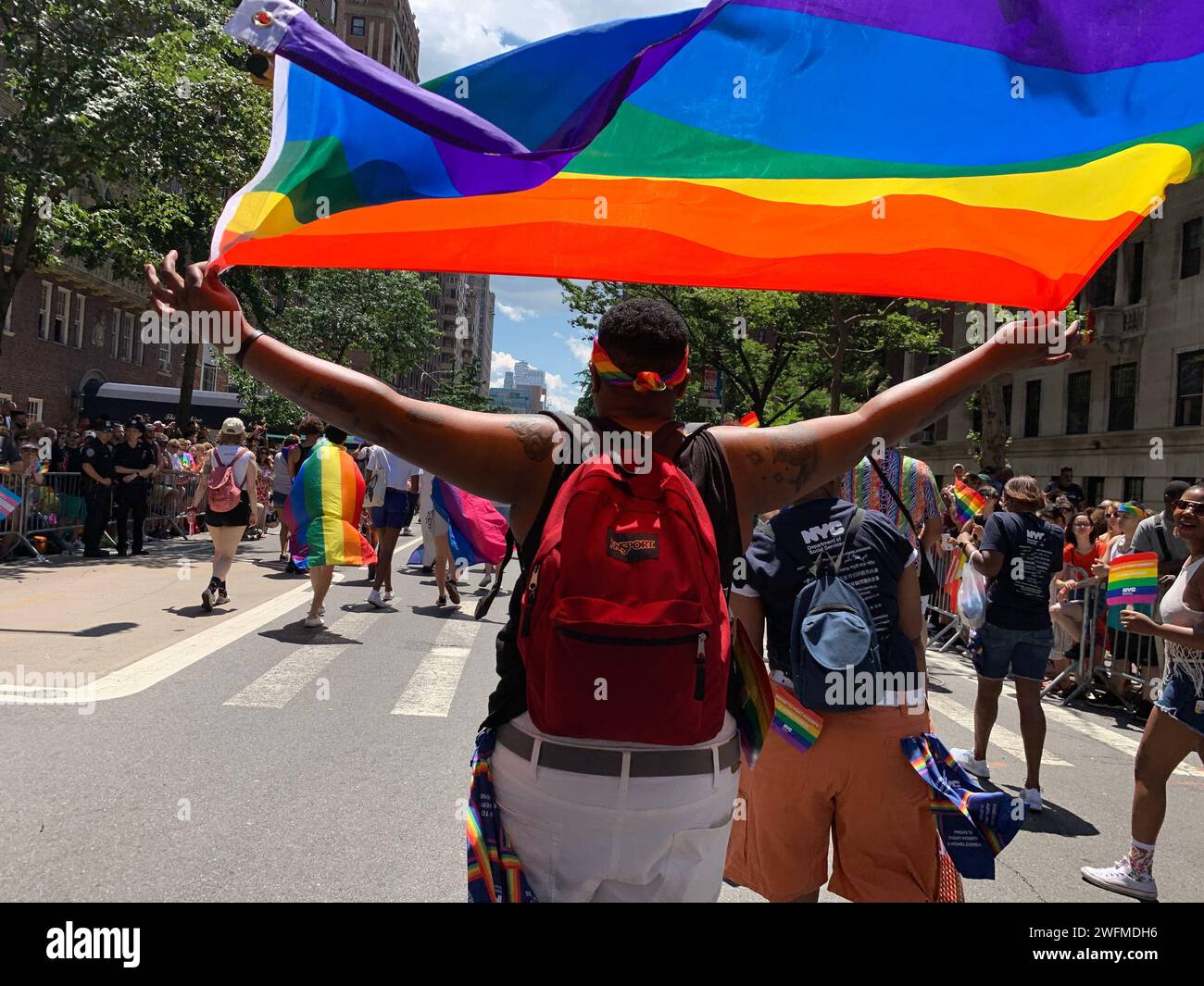 Un giovane alza la bandiera dell'arcobaleno sulla sua testa mentre marcia nella New York Pride Parade per celebrare la comunità LBGT Foto Stock