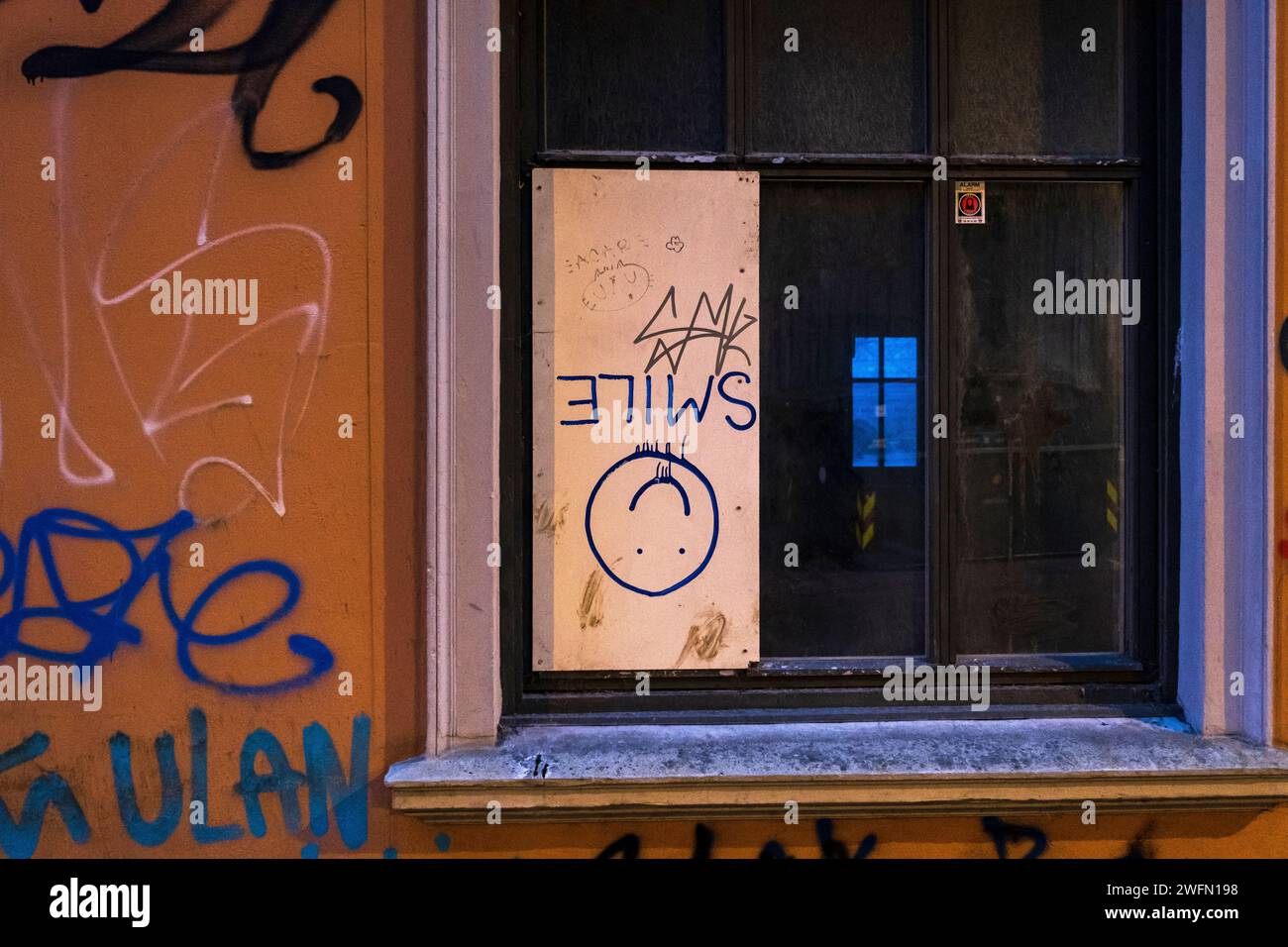 "Sorriso", faccia sorridente su una tavola di legno in una finestra di vetro rotta Foto Stock