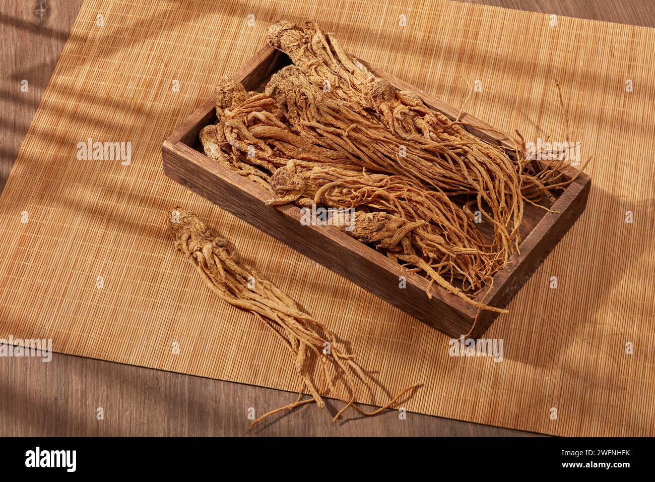 Radice di Angelica sputata su un vassoio di legno e tende di bambù. Le persone usano la radice di Angelica (Angelica sinensis) per abbellire, migliorare la salute e trattare il circolatore Foto Stock