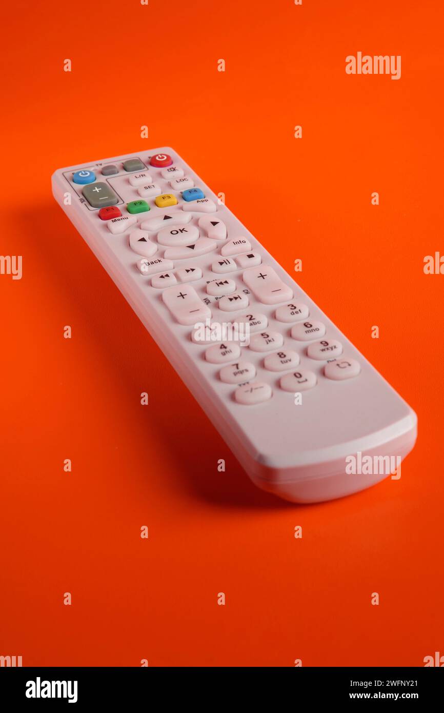 Un telecomando del televisore con vari tasti funzione su uno sfondo illuminato Foto Stock
