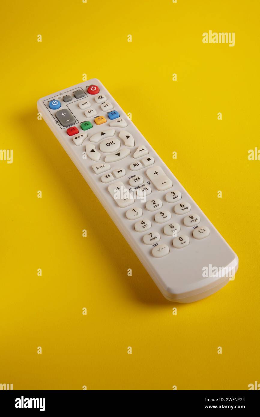 Telecomando di un televisore con vari tasti funzione su sfondo giallo Foto Stock