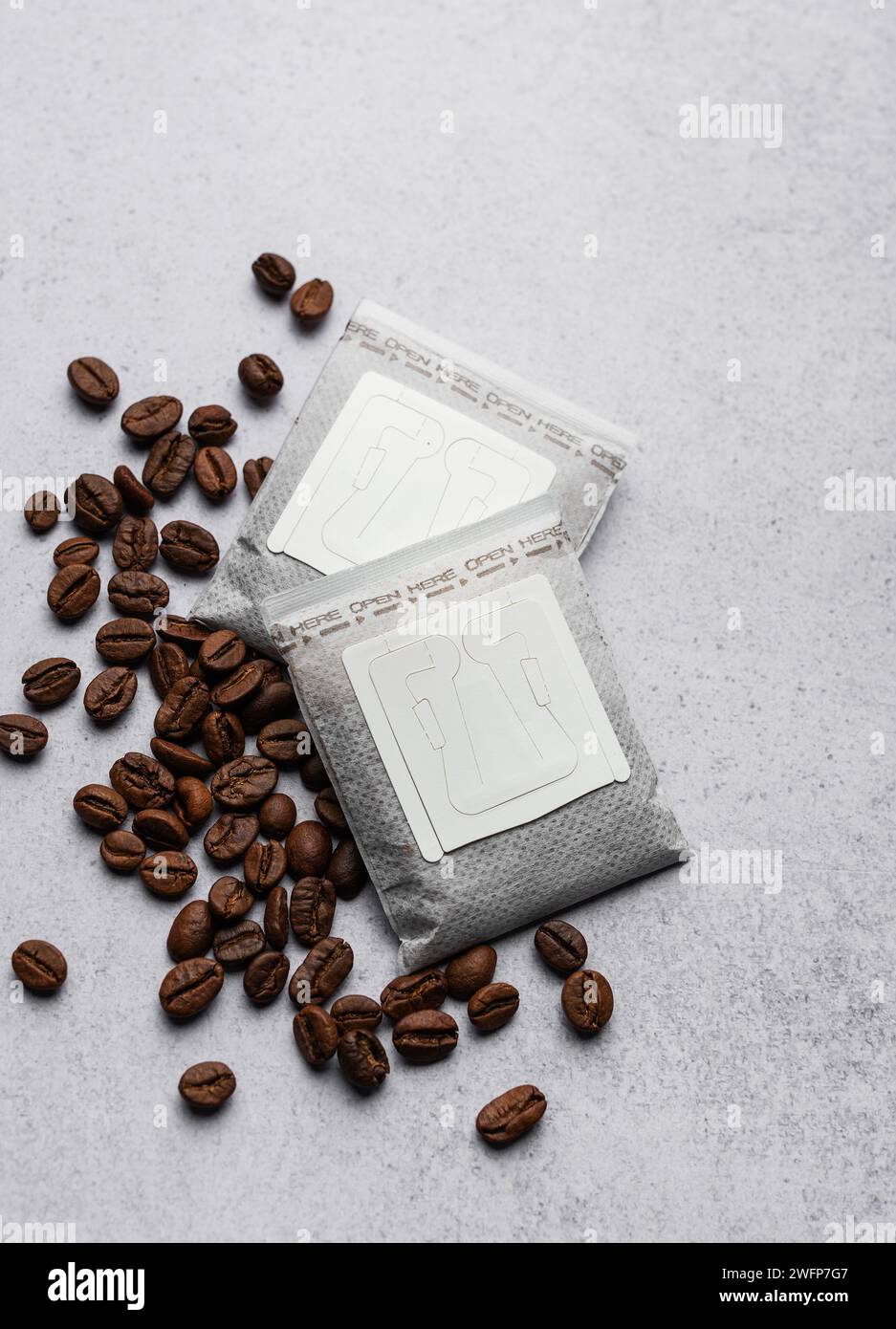 Versare i sacchetti di carta del caffè con i chicchi di caffè su uno sfondo grigio di cemento Foto Stock