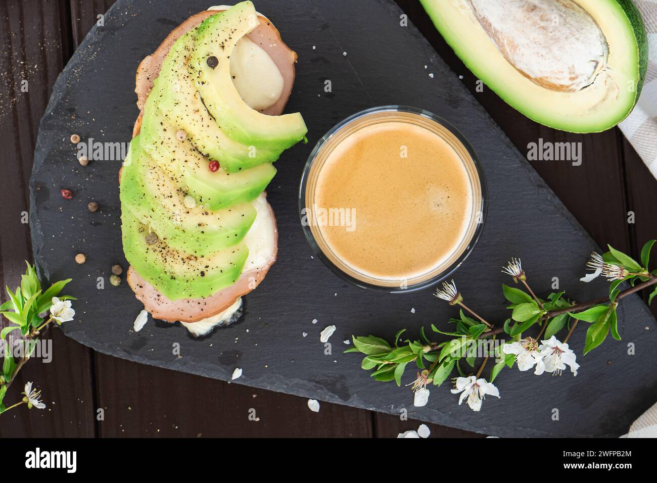 Colazione salutare. Pane integrale tostato con avocado fresco a fette, prosciutto, formaggio e tazza di caffè Foto Stock
