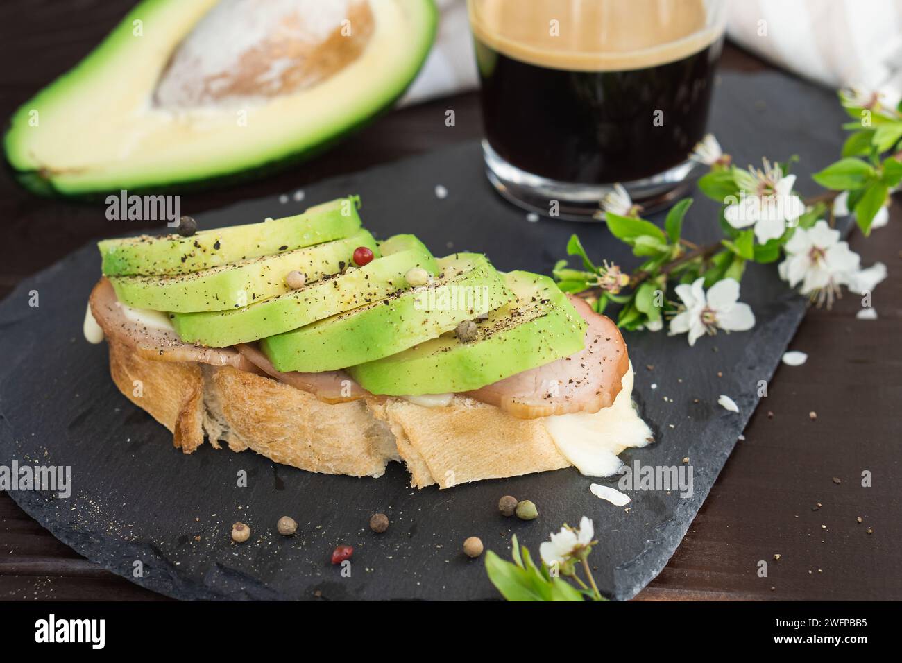 Colazione salutare. Pane integrale tostato con avocado fresco a fette, prosciutto, formaggio e tazza di caffè Foto Stock