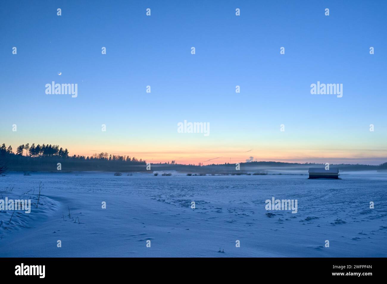 Un tramonto che proietta una calda luce su un paesaggio innevato Foto Stock