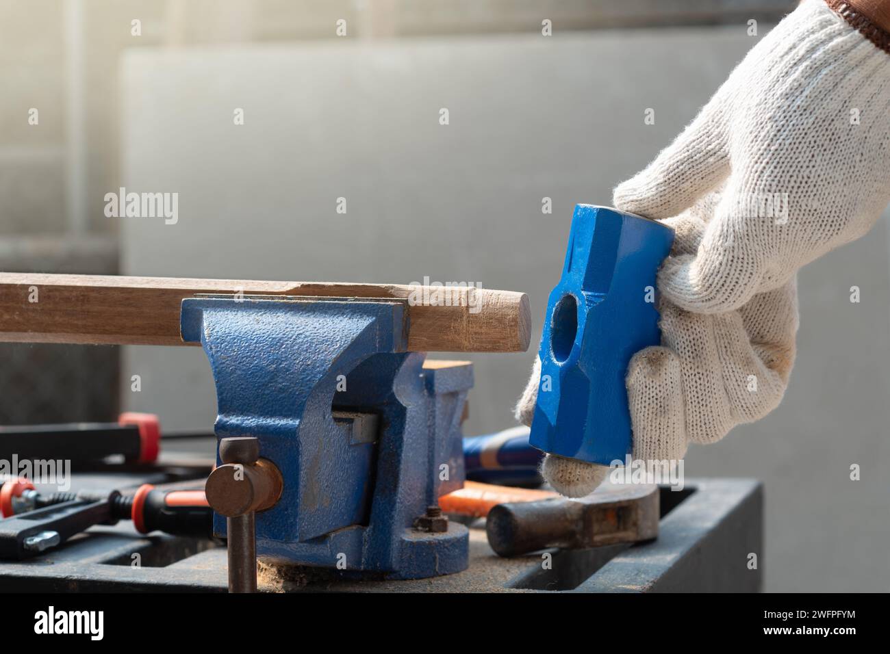 Pensione per hobby maschile. L'uomo anziano utilizza una morsa da banco su legno per il montaggio dell'impugnatura del martello. Foto Stock