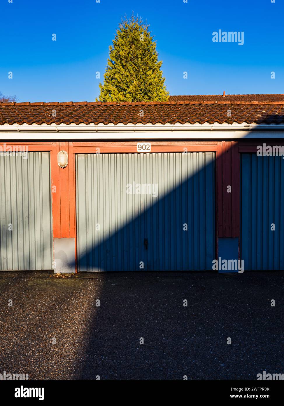 Il sole proietta un'ombra netta sulla parete ondulata di un garage blu sotto un cielo azzurro. Foto Stock