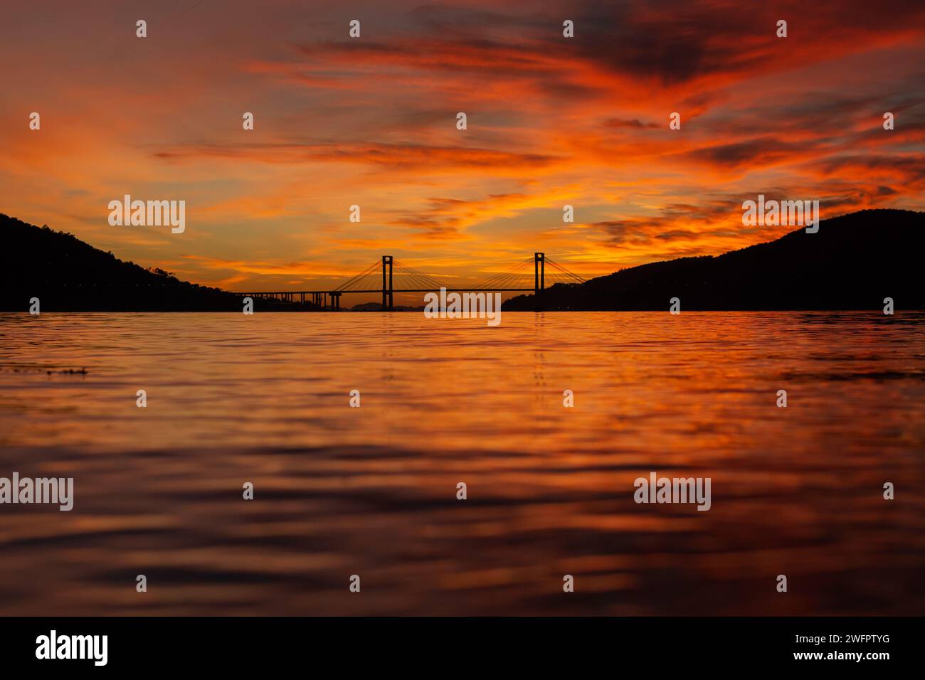 Vista sul ponte di Rande e sull'estuario di Vigo dalla spiaggia di cesantes in un incredibile tramonto arancione in Galizia Foto Stock