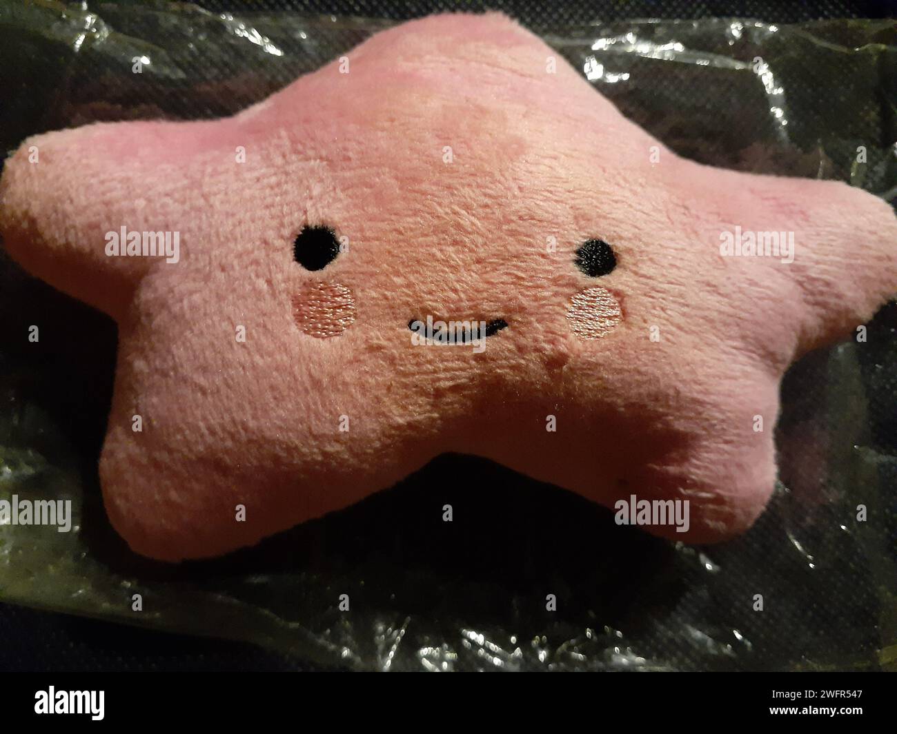 Cuscino rosa a stella con viso adorabile con occhi e guance rosate Foto Stock