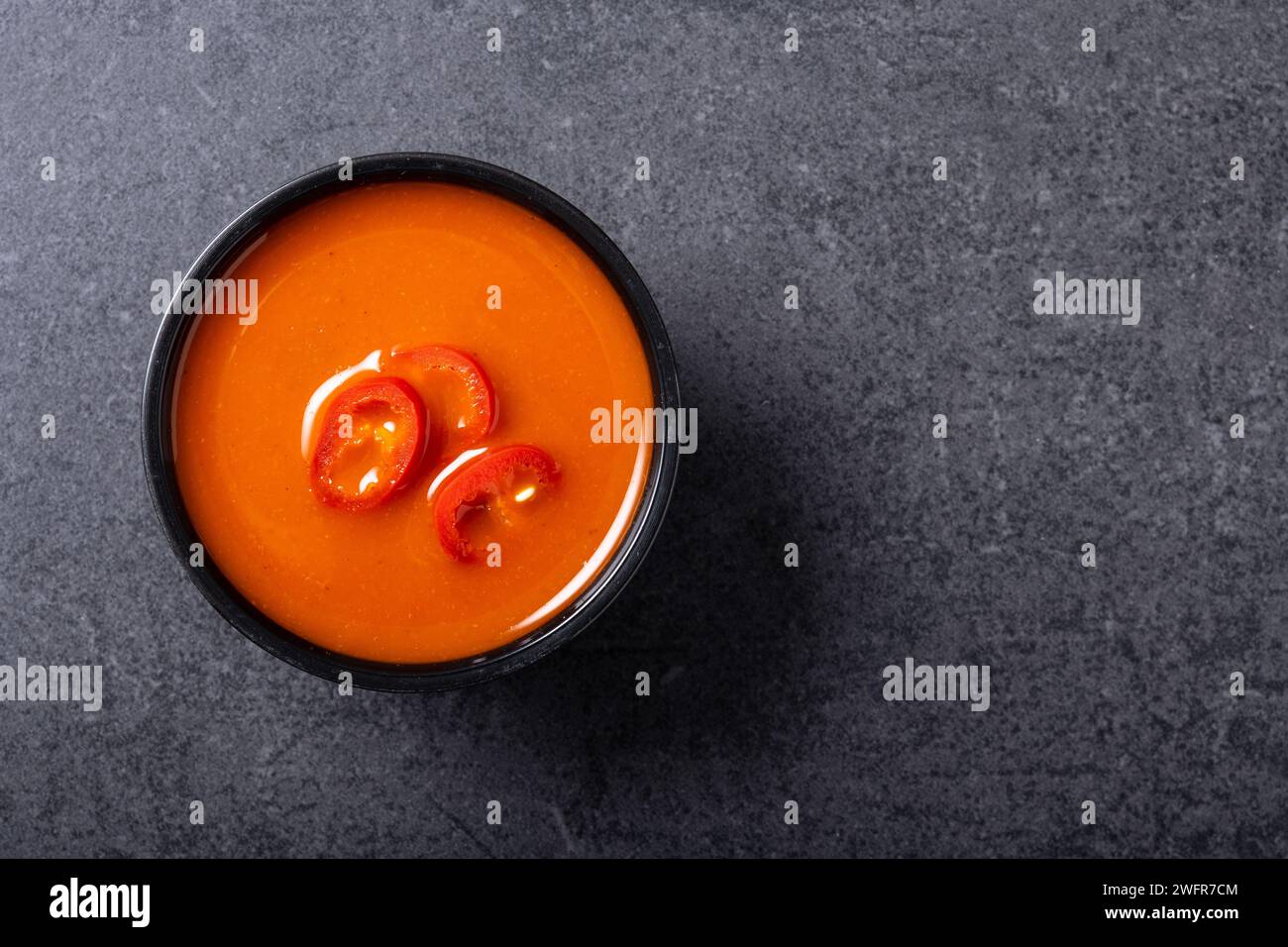 Salsa piccante al peperoncino in un recipiente su sfondo nero. Foto Stock