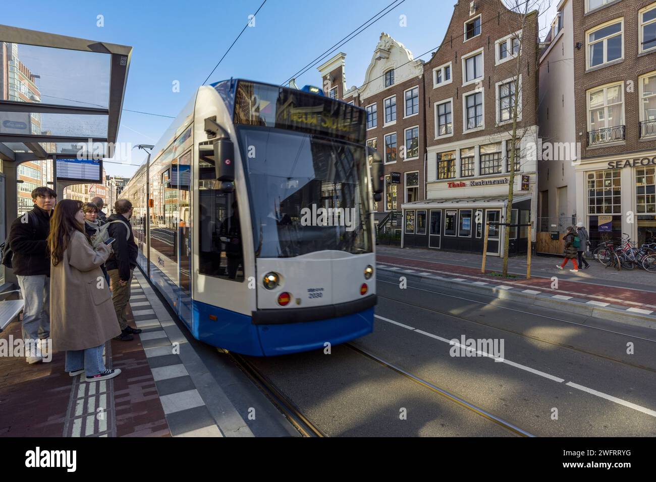 Gente in attesa di un tram a Nieuwezijds Voorburgwal nel centro di Amsterdam, Olanda settentrionale, Paesi Bassi. Foto Stock