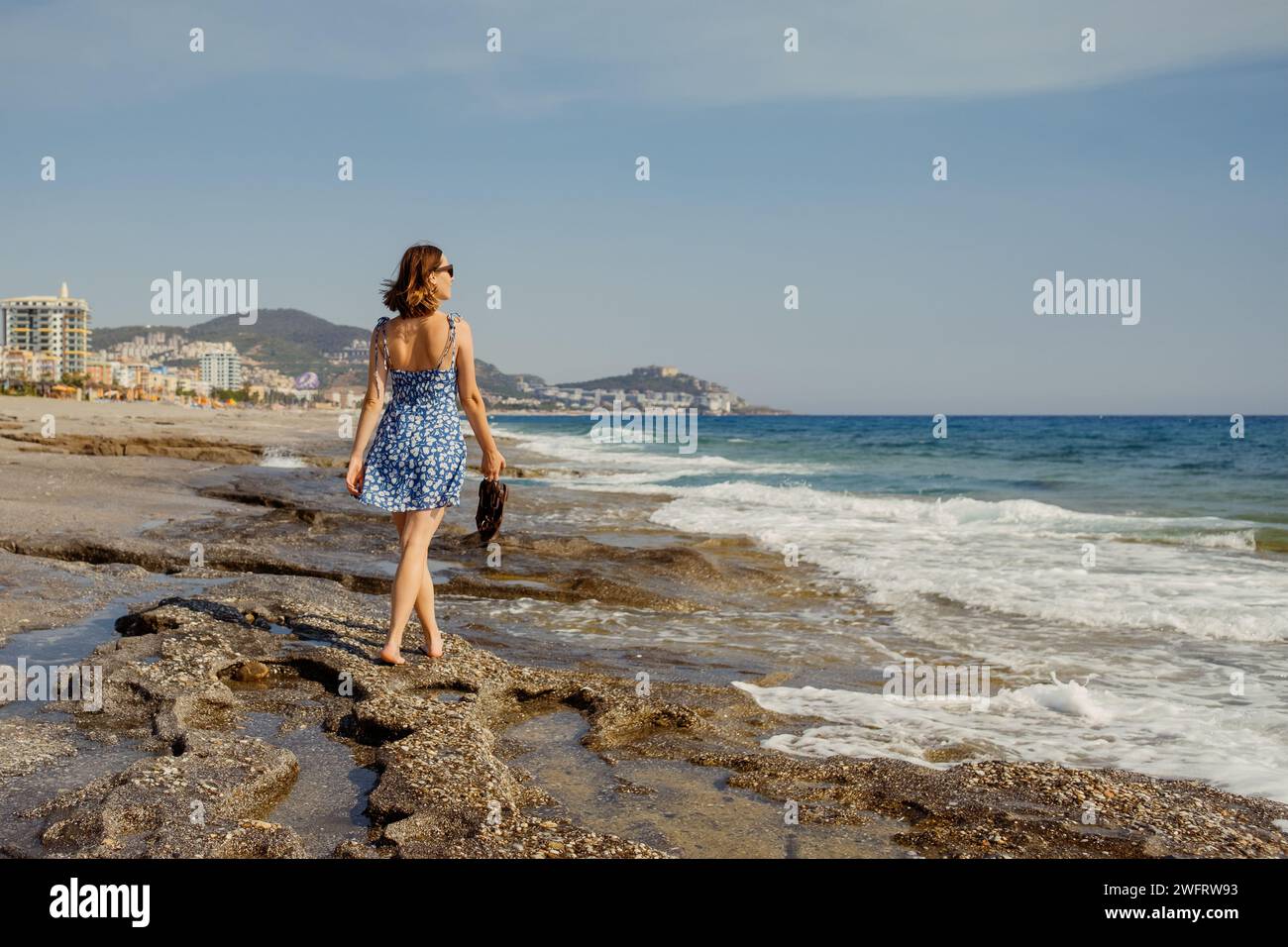 Eleganza marinara: Passeggia in riva al mare con un abito estivo Foto Stock