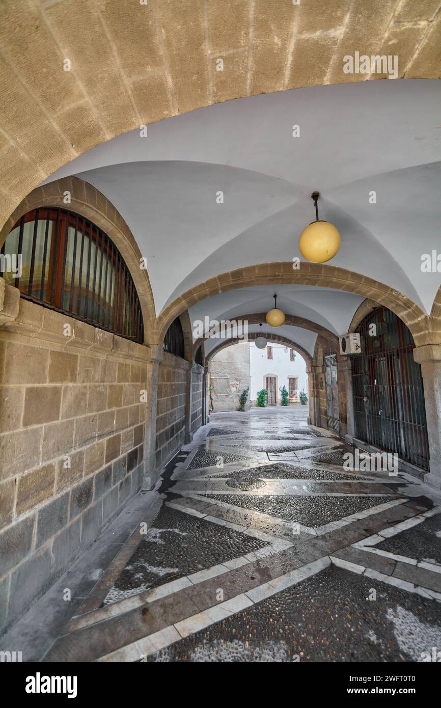 Corridoio in pietra con luci a sospensione che conducono a un luminoso spazio esterno, che mostra la bellezza architettonica di Jerez de la Frontera. Foto Stock