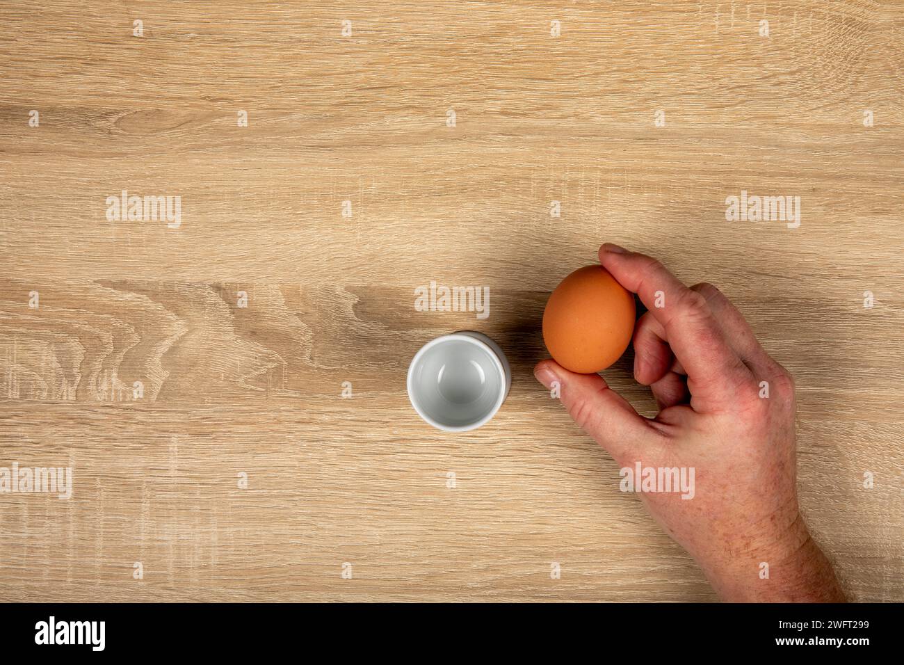 Colazione rustica da fattoria a tavola: Posizionamento di un uovo fresco nel supporto su un tavolo di legno, concetto di prezzi degli uovo. Foto Stock