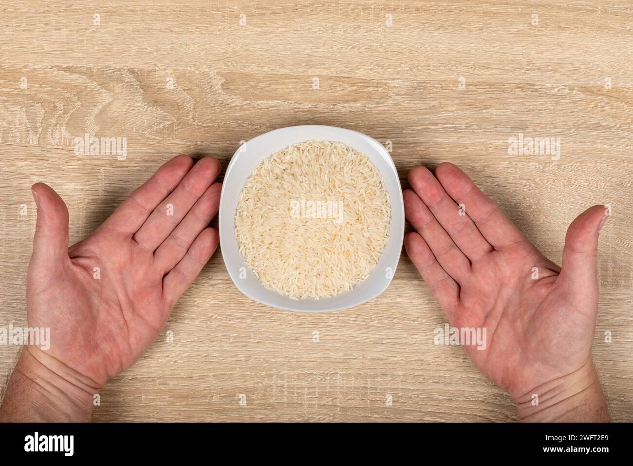 Mani che posizionano ciotola per riso bianco - concetto di emissioni di fame, cibo e gas serra agricoli, vista dall'alto. Foto Stock