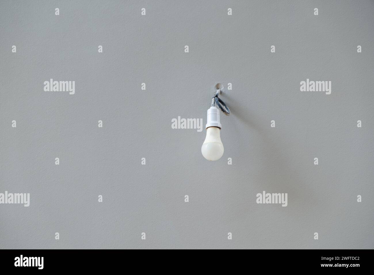 Concetto di risparmio energetico. Lampada elettrica isolata su sfondo bianco vuoto del soffitto. Lampada bianca appesa, attrezzatura per la casa. Copia spazio Foto Stock