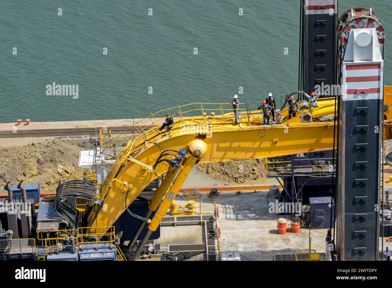 Canale di Panama, Panama - 23 gennaio 2024: Lavoratori in piedi sul braccio di un grande escavatore su una chiatta industriale utilizzata per dragare il Canale di Panama Foto Stock