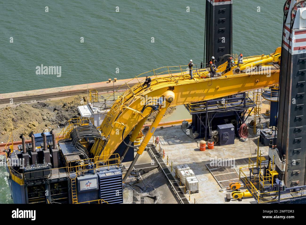Canale di Panama, Panama - 23 gennaio 2024: Lavoratori in piedi sul braccio di un grande escavatore su una chiatta industriale utilizzata per dragare il Canale di Panama Foto Stock